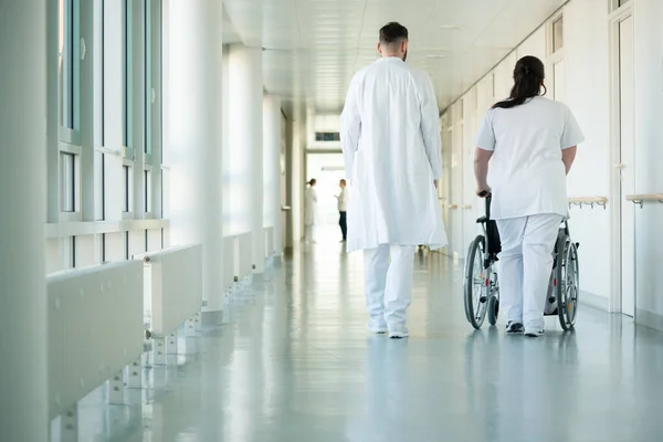 医生和护士推轮椅与女病人住院 — 图库照片