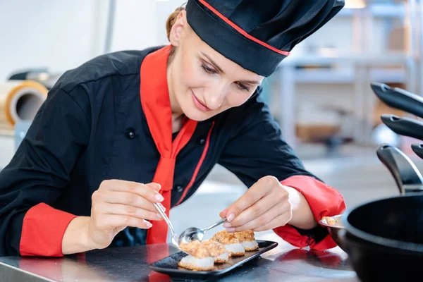 女厨师在一个黑色瓷盘里调料最后的开胃菜 — 图库照片