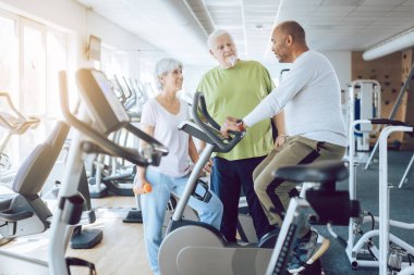 Spor salonunda egzersiz yapan üç kişi.