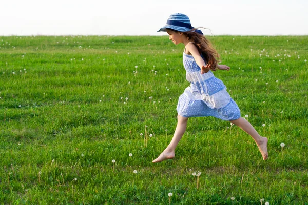 Dziewczyna biegnie na łące z mniszek lekarski — Zdjęcie stockowe