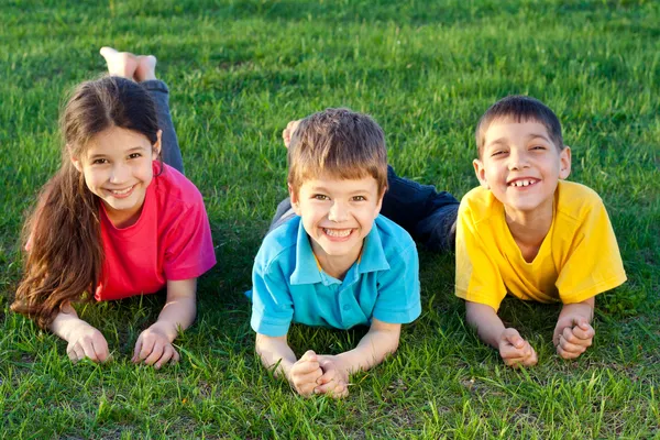 Трое улыбающихся детей на лугу — стоковое фото