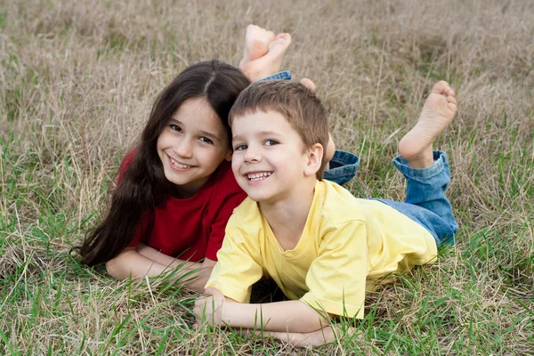 Two smiling kids on the autumn grass Stock Photo
