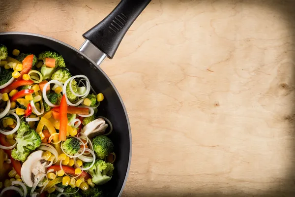 Freír verduras en sartén sobre fondo de madera — Foto de Stock