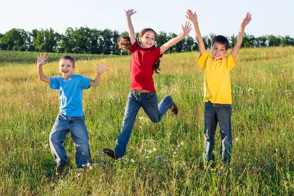 Jumping kids on green field — Stock Photo, Image