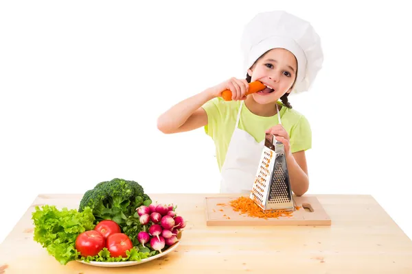 Девушка с теркой ест морковь — стоковое фото