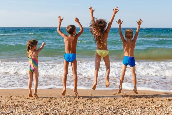 Czworo dzieci skoki na plaży — Zdjęcie stockowe