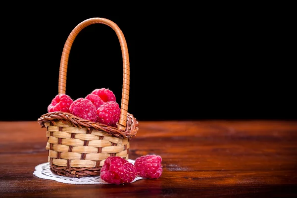 लकड़ी की मेज पर टोकरी में रास्पबेरी — स्टॉक फ़ोटो, इमेज