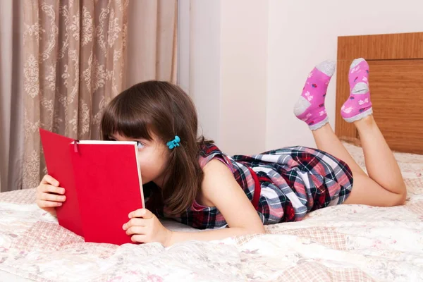Evde kitap okuyan küçük bir kız.