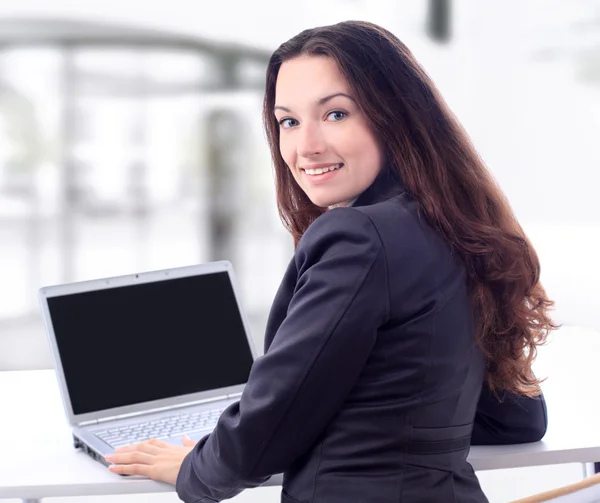 Femme d'affaires réfléchie pour un ordinateur portable dans le bureau avec un sourire . — Photo
