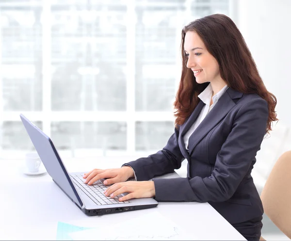 Femme d'affaires réfléchie dans le bureau pour un ordinateur portable avec un sourire . — Photo