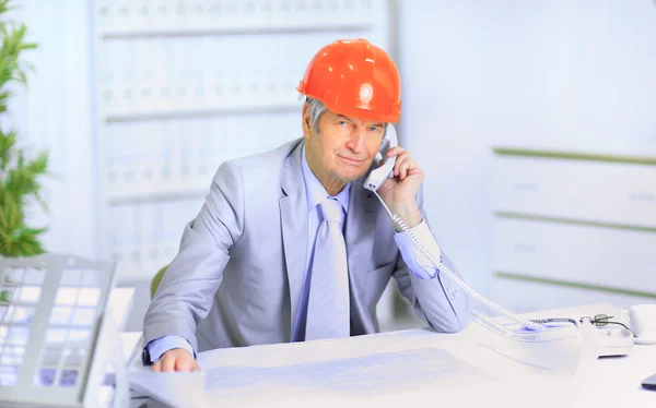 Inženýr ve věku mluví po telefonu o plánech výkresu. — Stock fotografie