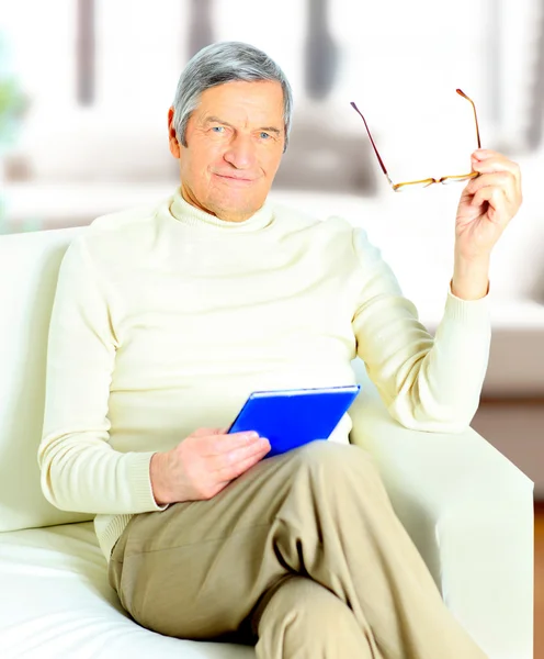 Homem idoso relaxando em casa com um livro — Fotografia de Stock