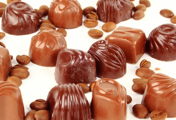 Dulces caramelos de chocolate y granos de café aislados sobre fondo blanco —  Fotos de Stock