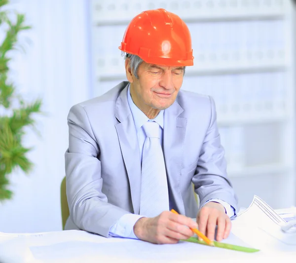 Engineer at the age of considering plans drawing and corrects them. — Stock Photo, Image