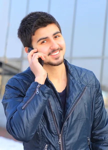 Ένας όμορφος νεαρός άνδρας σε απλό ρούχα, μιλώντας στο τηλέφωνο. — Φωτογραφία Αρχείου