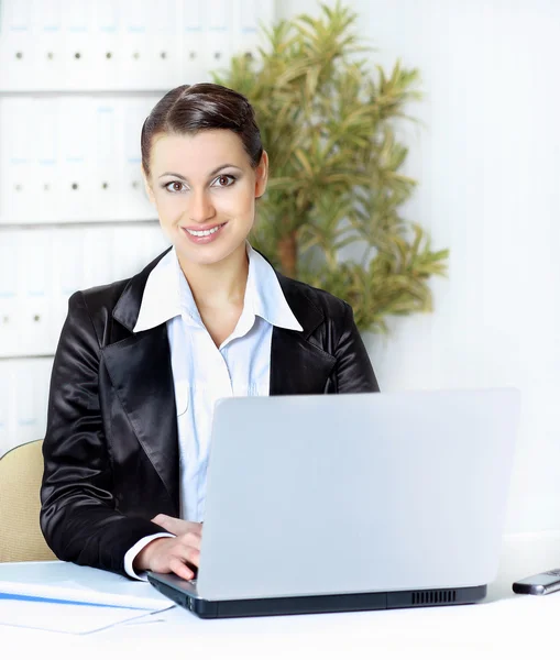 Mulher trativa com laptop nas mãos sorrindo, no escritório . — Fotografia de Stock