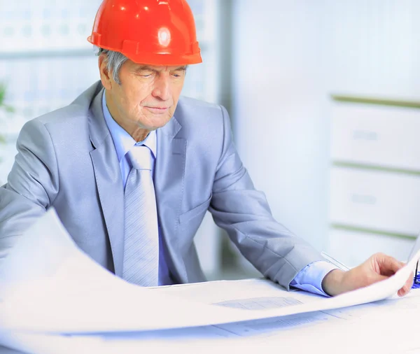 Engineer at the age of considering plans drawing and corrects them. — Stock Photo, Image