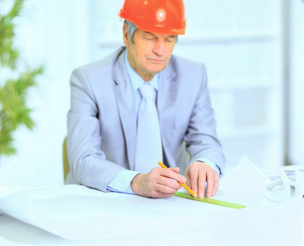 Ingenieur op de leeftijd van overwegen plannen tekening en corrigeert ze. — Stockfoto