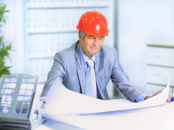 Engineer at the age of considering plans drawing and corrects them. — Stock Photo, Image