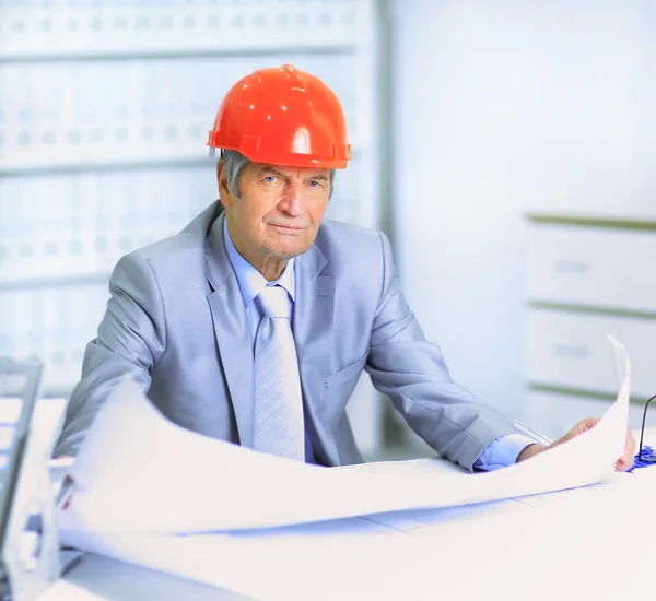 Engineer at the age of considering plans drawing and corrects them. — Stock Photo, Image