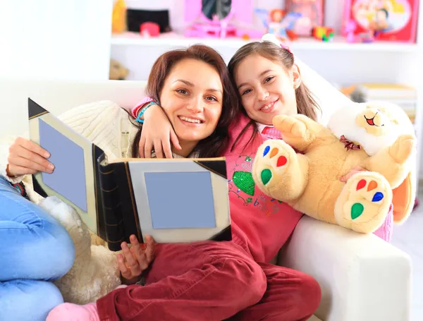 Mãe e filha felizes lendo um livro juntas — Fotografia de Stock