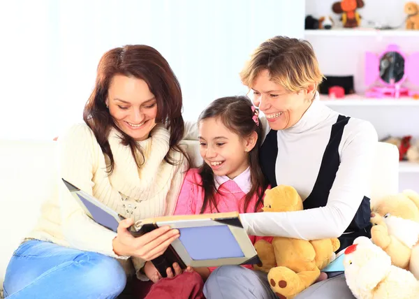 Grandmother, mother, and daughter reading a book together — Stock Photo, Image