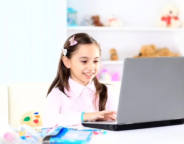 Ragazzina carina sorridente e guardando il computer portatile, Ragazzina usando il computer portatile — Foto Stock