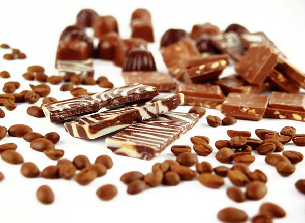 Dulces caramelos de chocolate y granos de café aislados sobre fondo blanco — Foto de Stock
