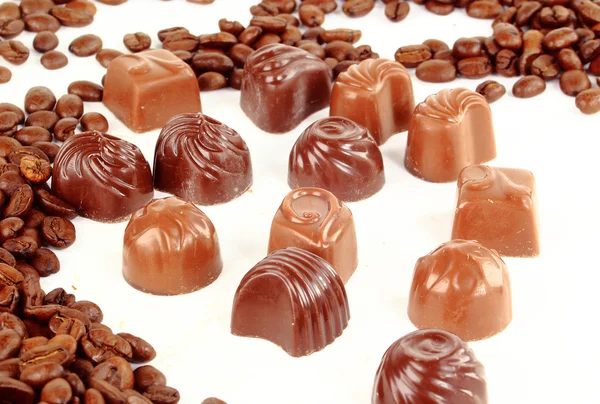 Zoete chocolade snoepjes en koffie bonen geïsoleerd op witte achtergrond — Stockfoto