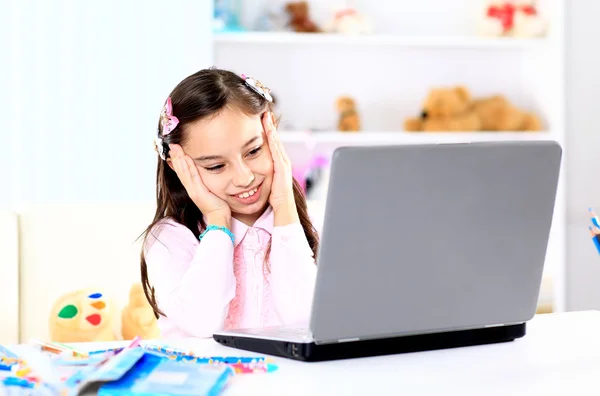 Linda niña sonriendo y mirando a la computadora portátil, Niña usando la computadora portátil —  Fotos de Stock