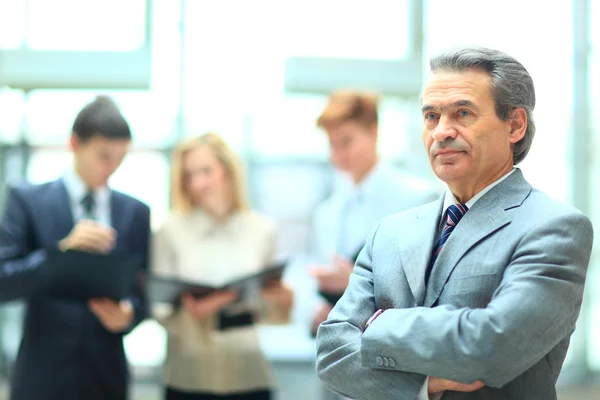 Homem de negócios inteligente feliz com companheiros de equipe discutindo em segundo plano — Fotografia de Stock