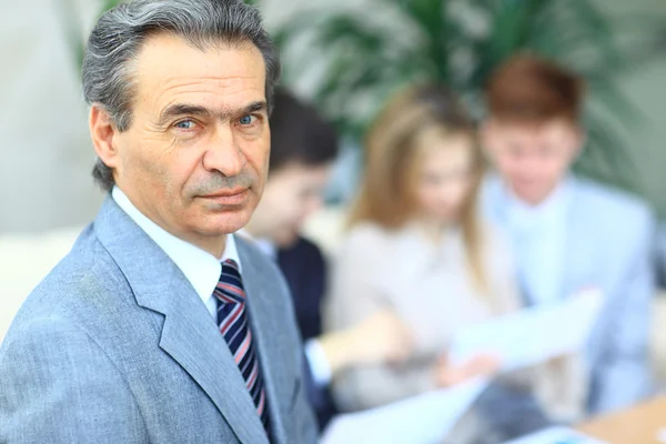 Feliz hombre de negocios inteligente con compañeros de equipo discutiendo en segundo plano — Foto de Stock