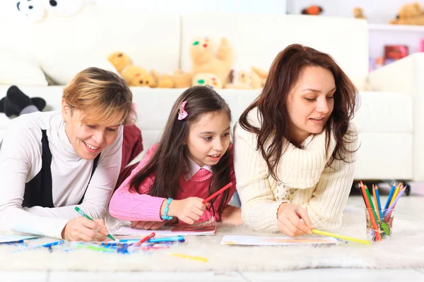 Belle fille dessine avec sa mère et sa tante . — Photo