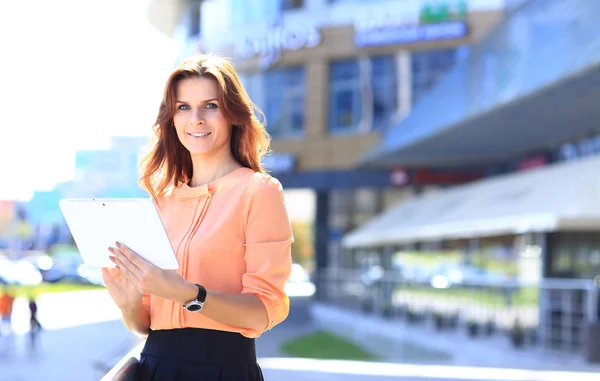 Mujer de negocios que trabaja en tableta digital al aire libre sobre el fondo del edificio —  Fotos de Stock