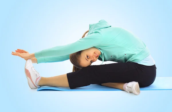 Een mooie jonge vrouw sporten op een blauwe achtergrond — Stockfoto