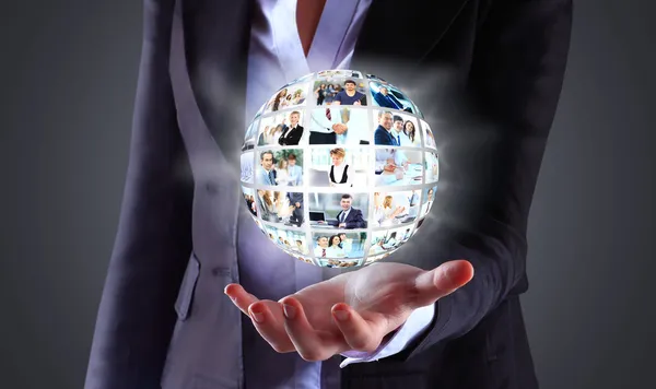 Business woman holding a ball of people on a dark background — Stock Photo, Image