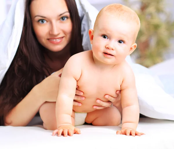 Família feliz. Mãe e bebê brincando e sorrindo sob um cobertor — Fotografia de Stock