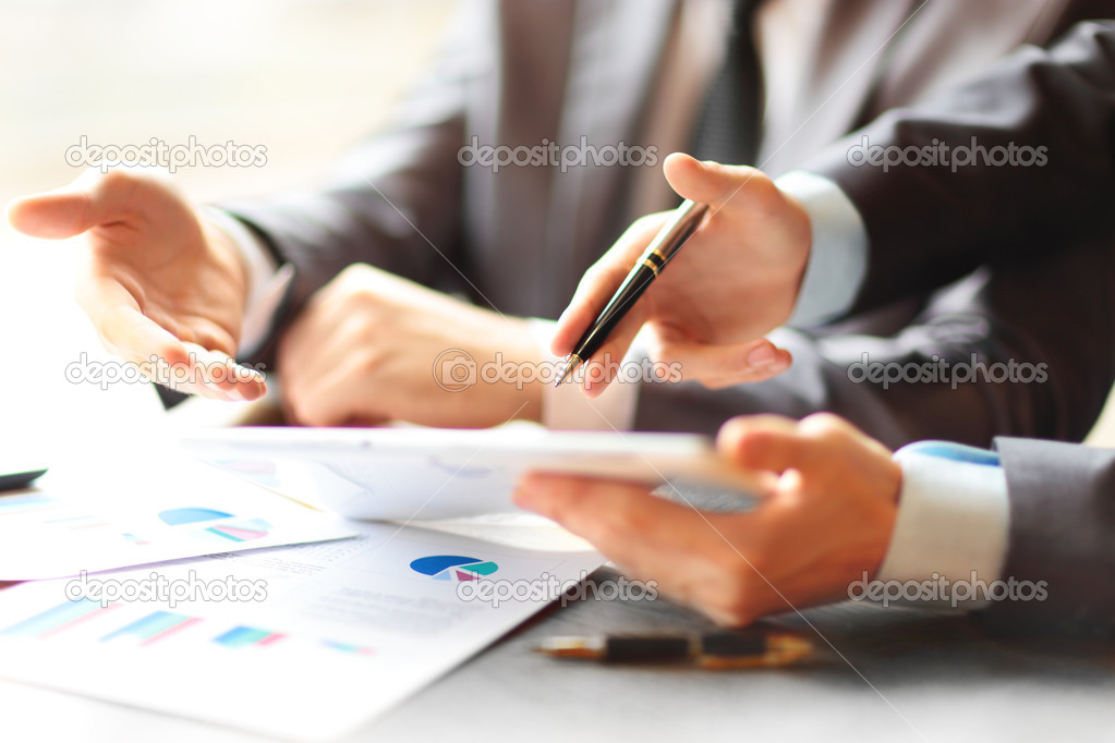 Two young businessmen using touchpad at meeting