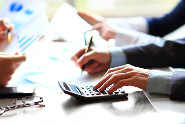 Empresários contando com calculadora sentados na mesa . — Fotografia de Stock