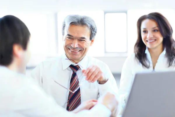 Ein dreiköpfiges Geschäftsteam, das im Büro sitzt und die Arbeit plant — Stockfoto