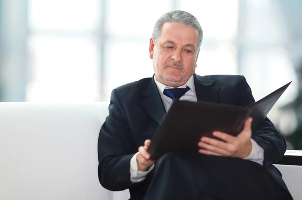 Handsome businessman sitting on the sofa in the office — Stock Photo, Image