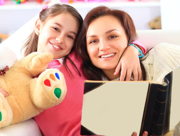 Happy mother and daughter reading a book together — Stock Photo, Image