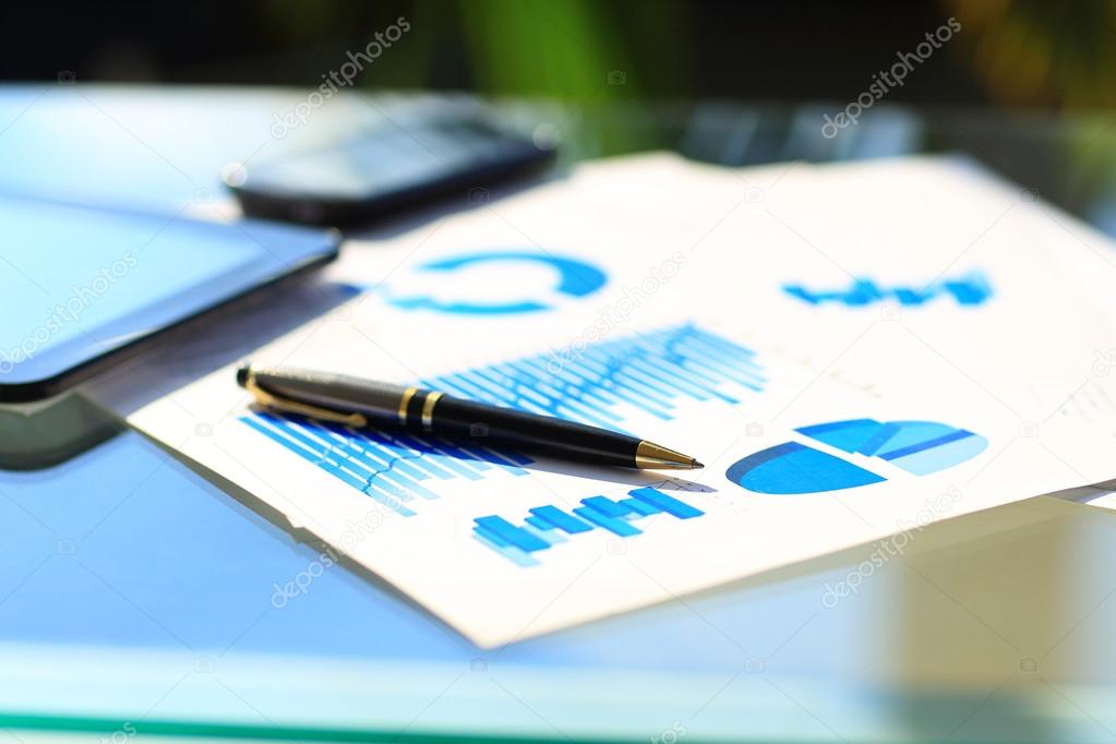 Financial charts on the table with tablet and pen