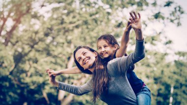 güneşli bir parkta kızıyla birlikte mutlu anne