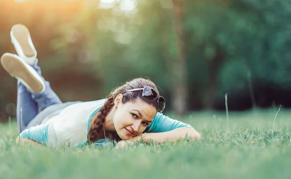 夏の日没に草の上に寝そべっている若い可愛い女性。自然 — ストック写真