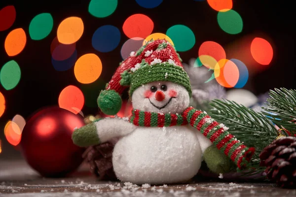 Muñeco de nieve alegre en un sombrero de punto sobre un fondo de Navidad. — Foto de Stock