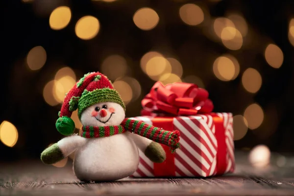 Divertente pupazzo di neve e una scatola con regali di Natale su uno sfondo festivo. — Foto Stock