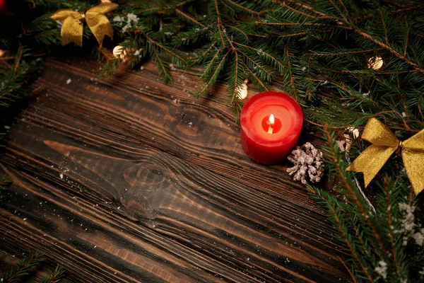 Vela de Natal e ramos de uma árvore de Natal em um fundo de madeira . — Fotografia de Stock