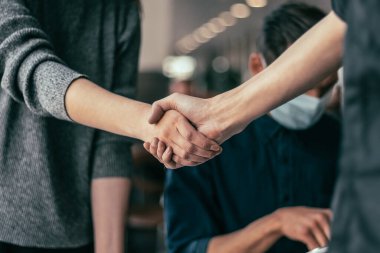 Koruyucu maskeli genç personel el sıkışıyor..