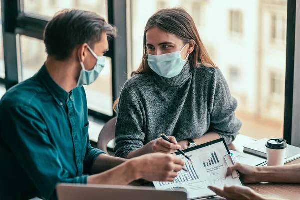 Jonge vrouw in een beschermend masker praten met haar collega. — Stockfoto